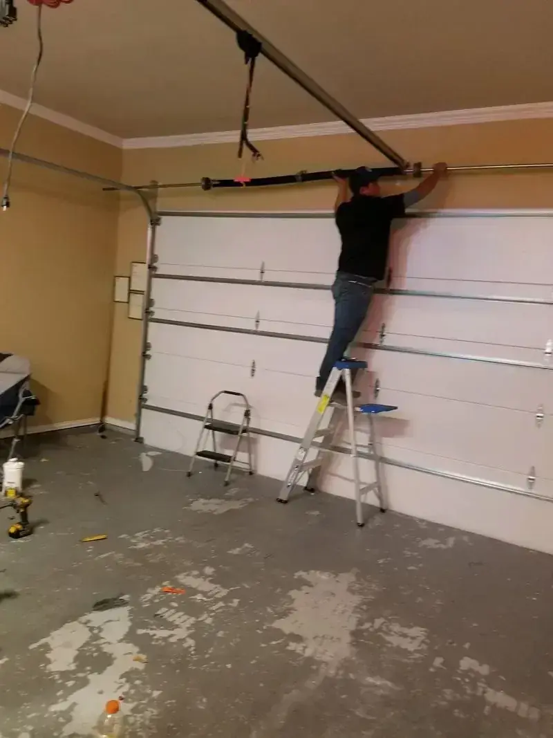 A man on a ladder working on a garage door