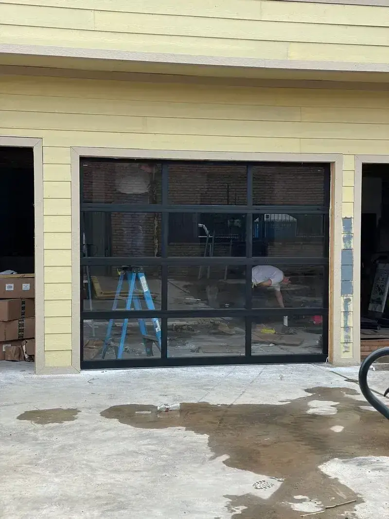 A man is standing in front of a garage door that is being installed.