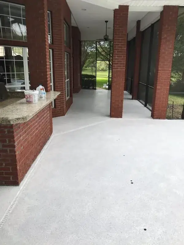 A screened in porch with a brick wall and a white floor